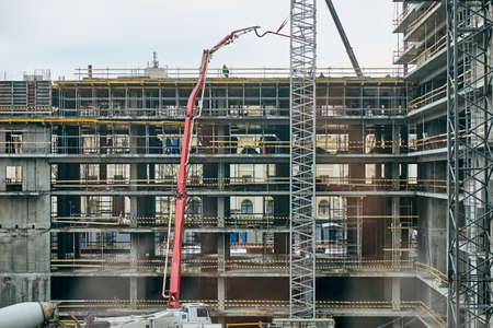 Construction worker standing on top of an unfinished building with finished apartment blocks in the backgroundの写真素材