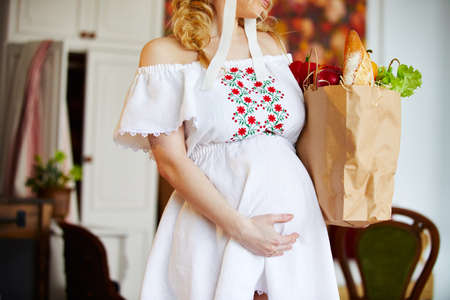 Young pregnant woman in the kitchen. Healthy food for pregnant womenの写真素材