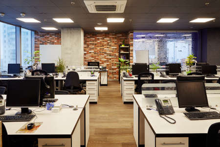 Moscow, Russia, 02.03.2019: Working Place on grey Table with Laptop Computer green Flower red Chair and Pencils in modern Office interiorのeditorial素材