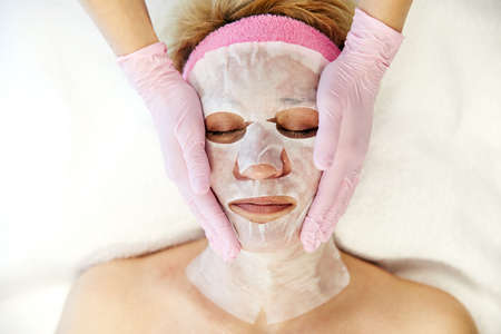 Moscow, Russia, 02.02.2019: Beautiful woman with facial mask at beauty salon. Applying facial mask at woman face at beauty salon.のeditorial素材