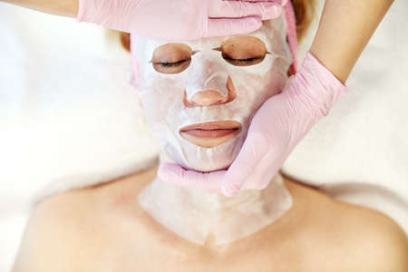 Moscow, Russia, 02.02.2019: Beautiful woman with facial mask at beauty salon. Applying facial mask at woman face at beauty salon.のeditorial素材