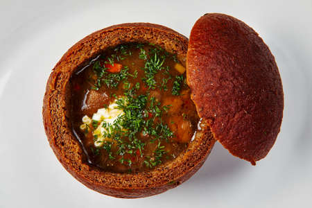 Restaurant food. Rustic closeup of red the soup in bread on white backgroundの写真素材