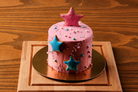 pink cake with asterisks on a wooden board, pastries in icing