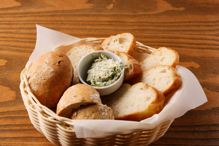 sliced loaf, with cheese in a white bowl, folded in a wicker basket