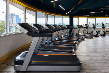 treadmills hardly standing in front of large windows, gym, sports and fitness equipment for jogging