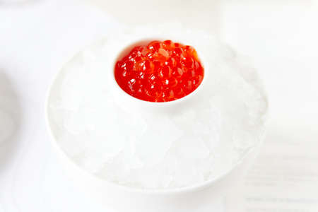 Red caviar, in a white saucer, standing in ice on a white background, seafoodの写真素材