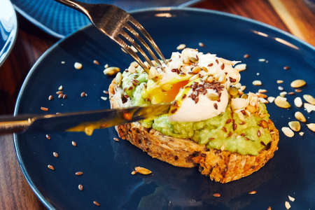 sandwich, white bread with avocado herbs and spices, with a soft-boiled egg, which is cut with a knifeの写真素材