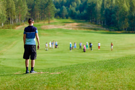 a man standing on a huge green field, amid many other people, nature and forestの写真素材