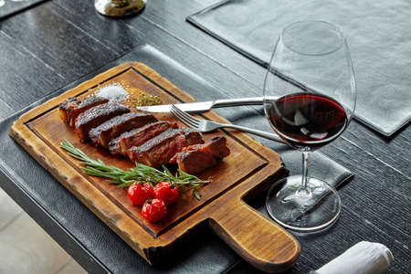 fried boiled pork, cut into slices, lying on a wooden board, decorated with tomatoes, tarragon, herbs, close-upの写真素材