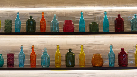 multi-colored bottles of different shapes stand in a row on wooden shelvesの写真素材