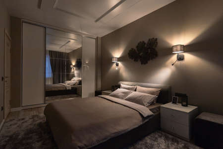 Russia, Moscow, 07.03.2019, The interior of the bedroom, in white colors, with a large wardrobe and a large white bed and off lightsのeditorial素材