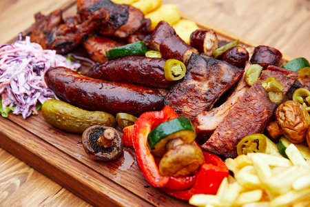 meat sausages and meat laid out on a wooden board with potatoes and vegetables
