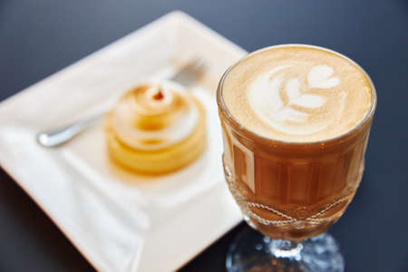 a glass of coffee with foam with a pattern on a gray background with a framedの写真素材