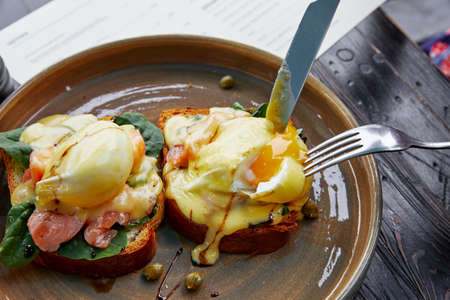two sandwiches with a basil egg and ham, with spices and herbs, which are cut with a knife and a forkの写真素材