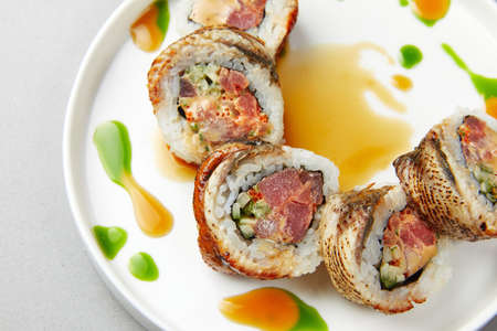 Sushi Uramaki with salmon, green algae, rolls poured with sauce wrapped in fish and, with spicesの写真素材