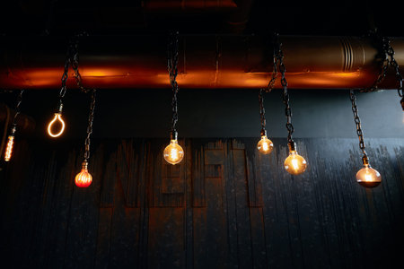 burning lamps of different sizes hang on chains in a row