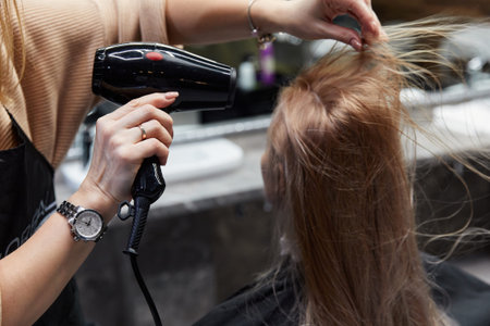 hairdresser dries girl long blond hair at the hairdresser