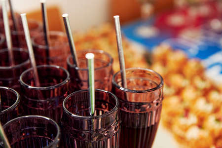 drinks poured into glass glasses with a straw stand in a rowの写真素材