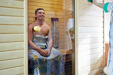 Russia, Moscow, 03.20.2020, a man with a naked torso wrapped in a towel sits in a steam bath in self-isolationのeditorial素材