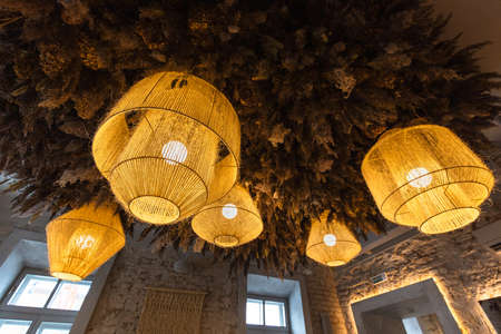 luxurious burning chandeliers of various shapes, in a restaurant, yellow, with plants on the ceilingの写真素材