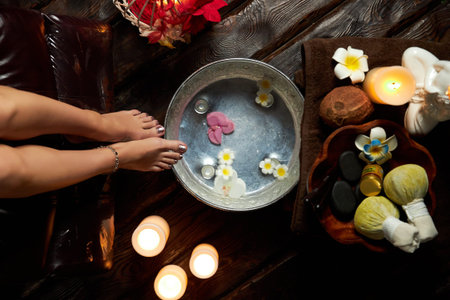 Hot water with flowers for steaming feet, spa treatment, candles and fruitsの写真素材
