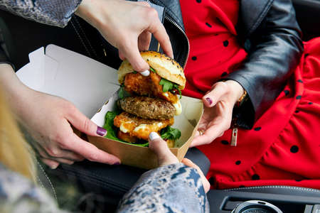 big juicy hamburger with cheese, with two cutlets, people watching the fillingの写真素材