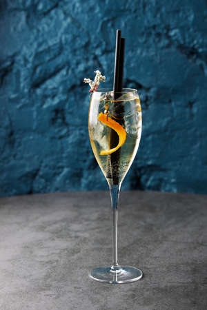 Champagne in a glass with orange peel and two tubesの写真素材