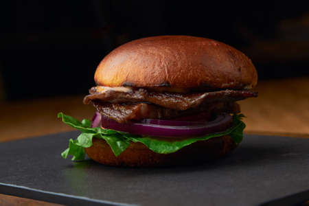 Large juicy dark hamburger with cheese on a dark backgroundの写真素材