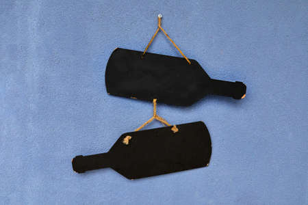 blank signs in the form of wine bottles hang on the blue wall, mocapの写真素材