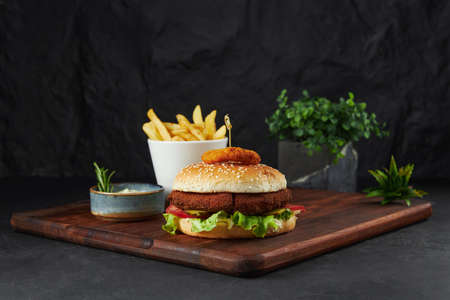 Hamburger with a large juicy cutlet, fries on a wooden boardの写真素材