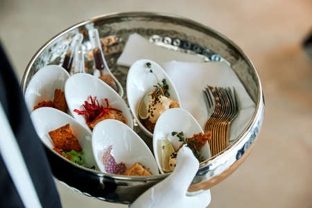 Seafood snacks on small plates that the waiter holds on a trayの写真素材