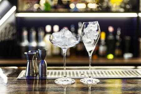 two glasses of different shapes with ice are on the barの写真素材