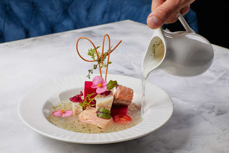 fish soup decorated with flowers, in which broth is pouredの写真素材