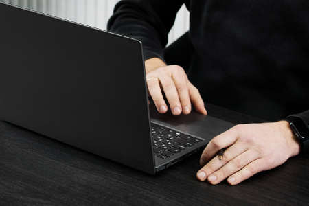 a man works at a laptop on a black table, handの写真素材