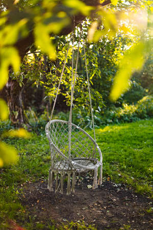 Empty egg chair with tinsels on tree branch in spring gardenの写真素材