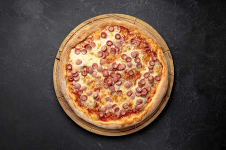 Fresh pepperoni pizza with cheese and sauce on black tableの写真素材
