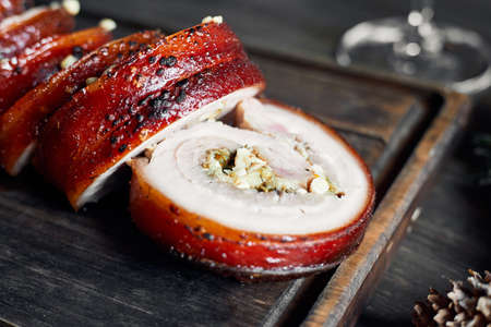 Delicious sliced porchetta on old wooden board macroの写真素材