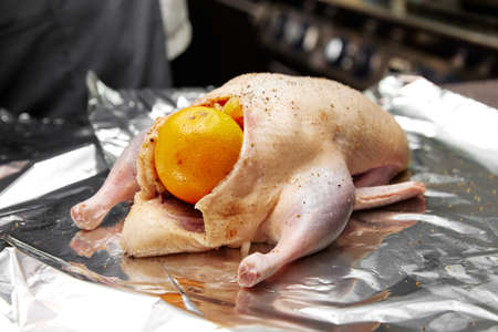 Raw duck with spices and orange on foil sheet in kitchenの写真素材