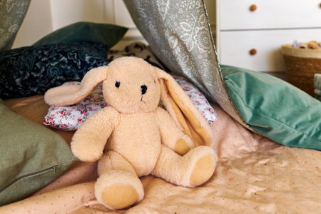 Soft toy bunny on bed with pillows and baldachin in bedroomの写真素材