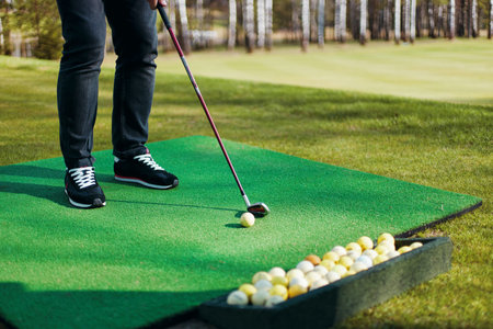 Man plays golf standing on artificial grass in sunny park