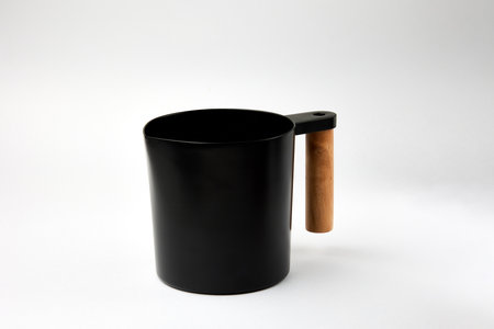 Black jar with wooden handle stands on white background. Spacious container with stylish design made for organic cosmetics close viewの写真素材