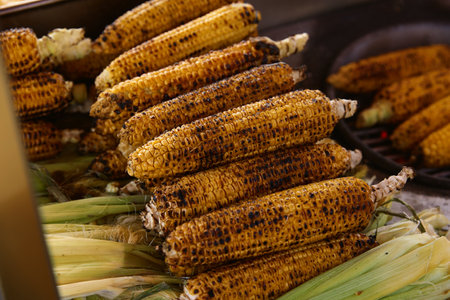 Corncobs grilled for arrived visitors on crowded beaches in touristic city. Preparation of touristic food for sale at resort and marketsの写真素材