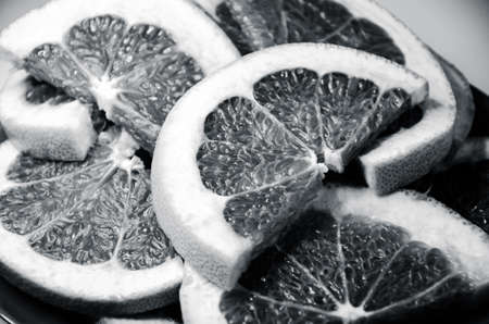 Closeup of slices of grapefruit. Fruit on the plate with white background. Grayscale photoの写真素材