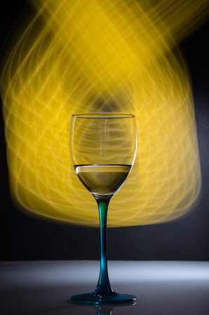 Wineglass on black background with yellow neon light painting behindの写真素材