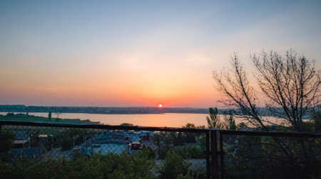 The sun rises over the river and the townの写真素材