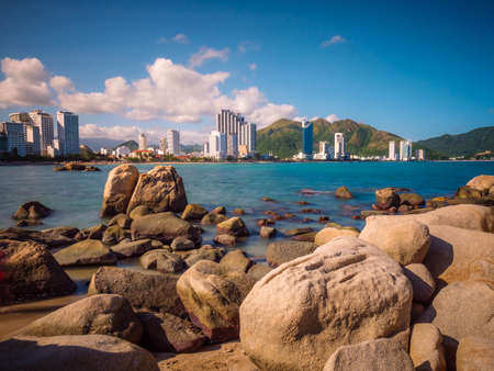 Rocks on the bayside with big city background. Tourist place with nice view. Summer vacation near oceanの写真素材