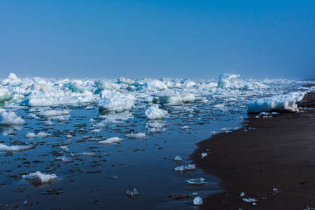 Drifting ice in the sea near the sandy coast. Ice in the sea near the beachの写真素材