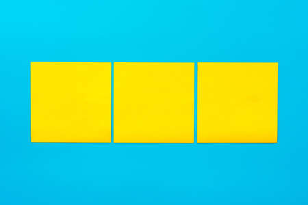 Reminder and combination concept- Close up three yellow empty square stickers on blue background with copy spase, mock up horizontal orientation.の写真素材