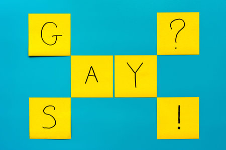 Sexual minority and coming out concept- Handwritten black inscription gay and say on yellow square...
