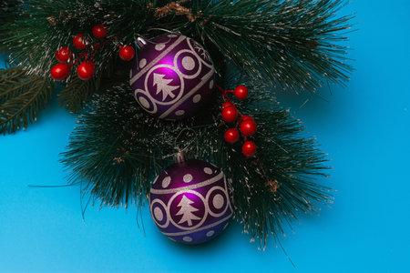 Two purple festive balloons with the image of a Christmas tree and snowflakes lie on artificial...